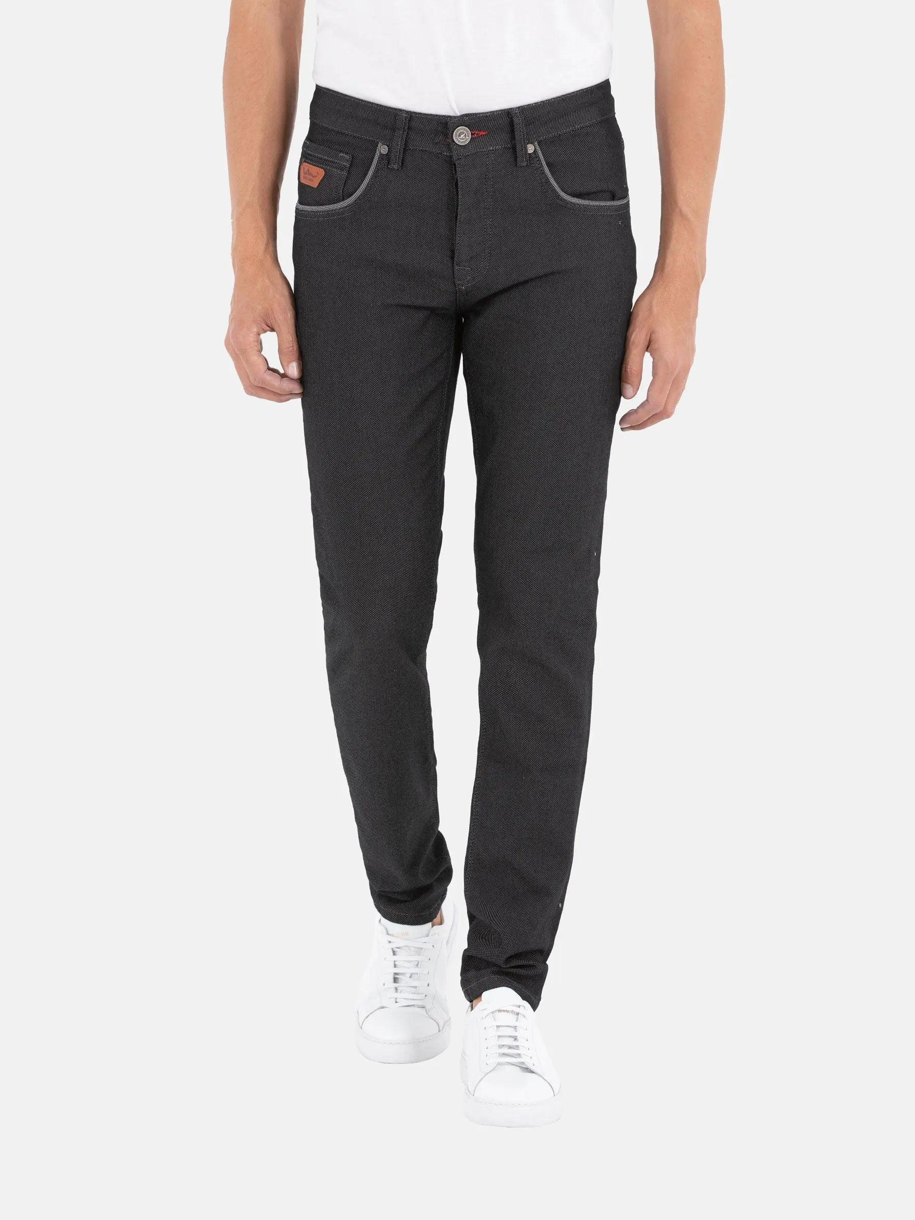 Man wearing slim-fit black patterned jeans with white sneakers and contrast stitching – Wam Denim.