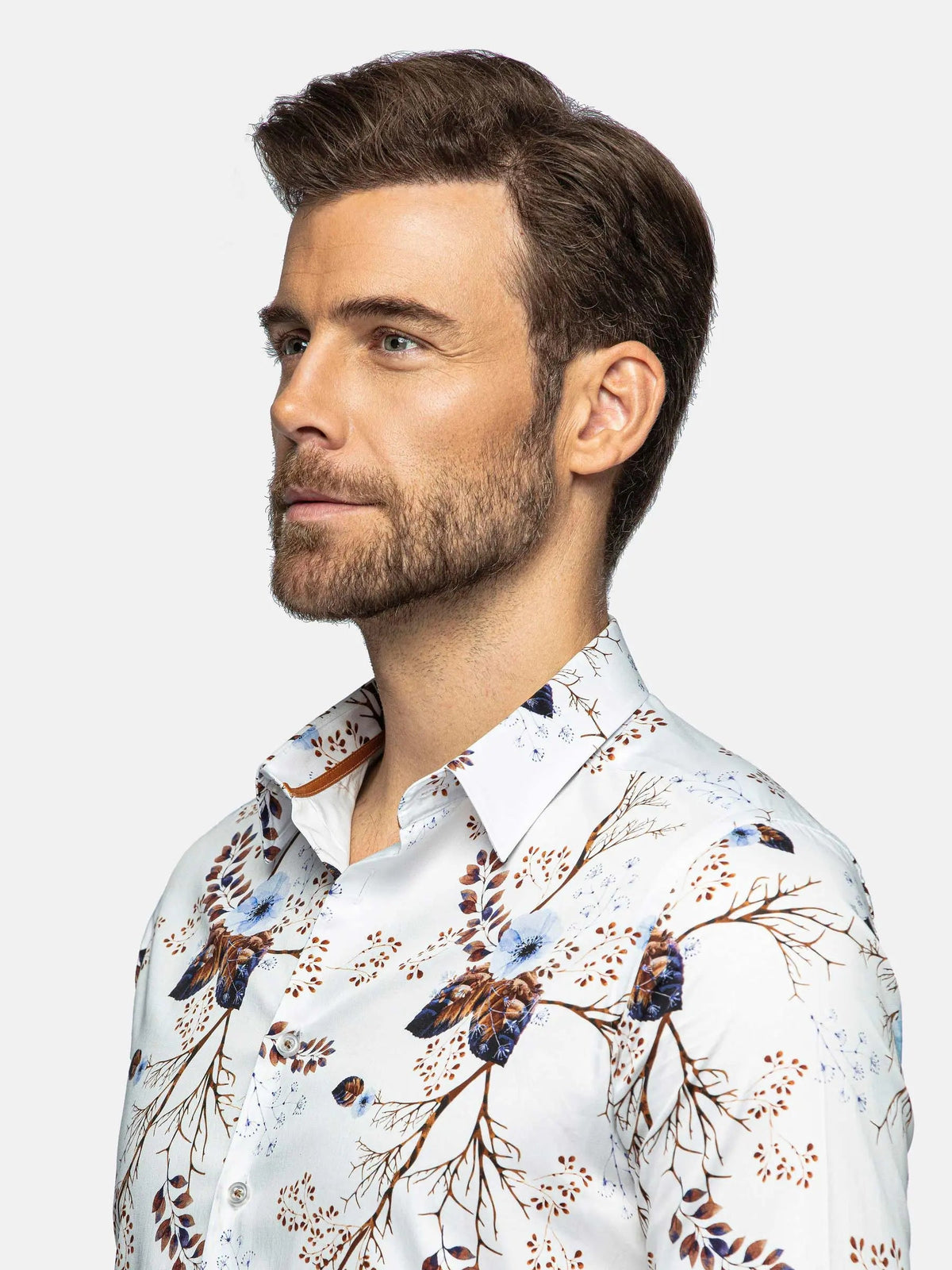 Man wearing a white shirt with a floral pattern on a light gray background