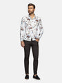 Man wearing a patterned shirt and dark pants on a white background