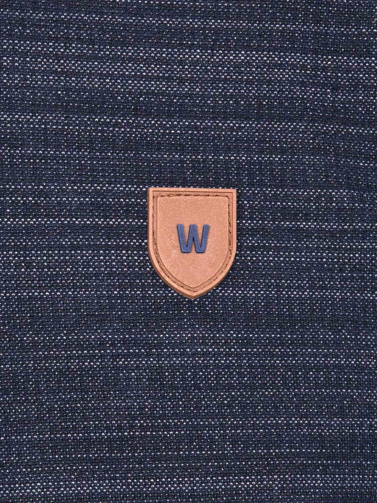 Close-up of a textured blue fabric with a brown leather patch featuring a 'W' logo.