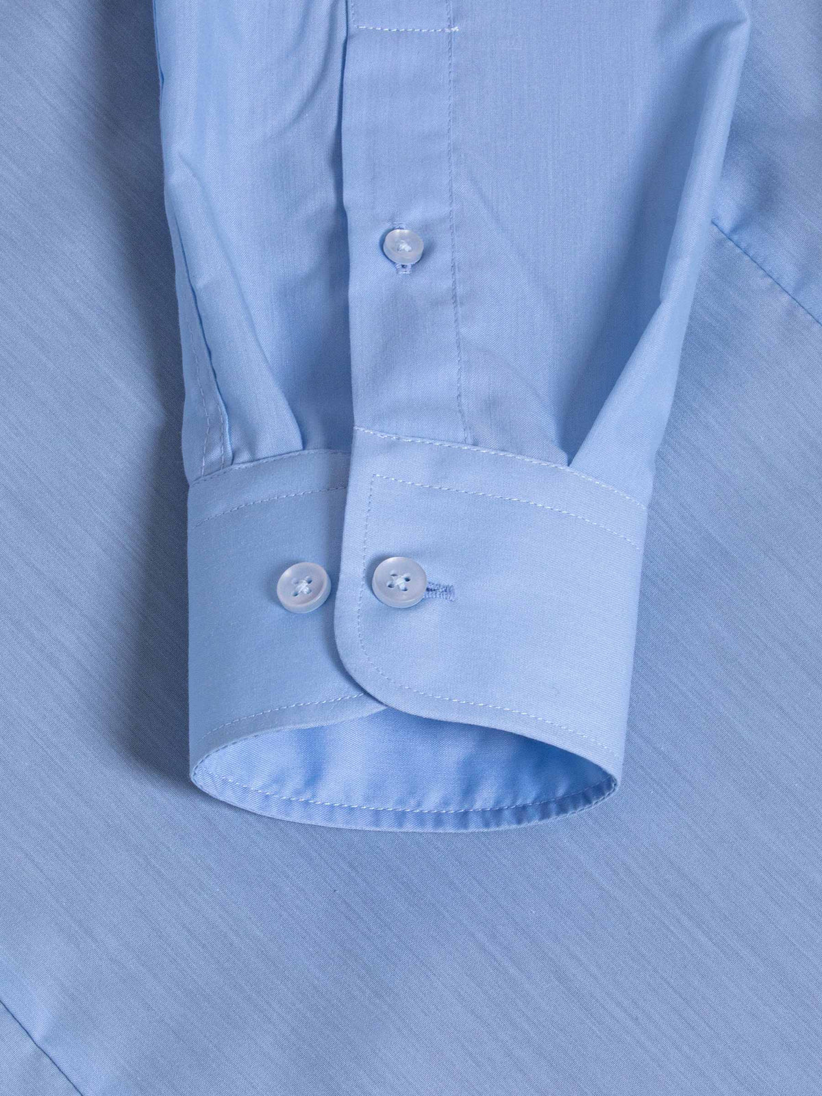 Close-up of light blue dress shirt cuff with double buttons and fine stitching – Wam Denim.