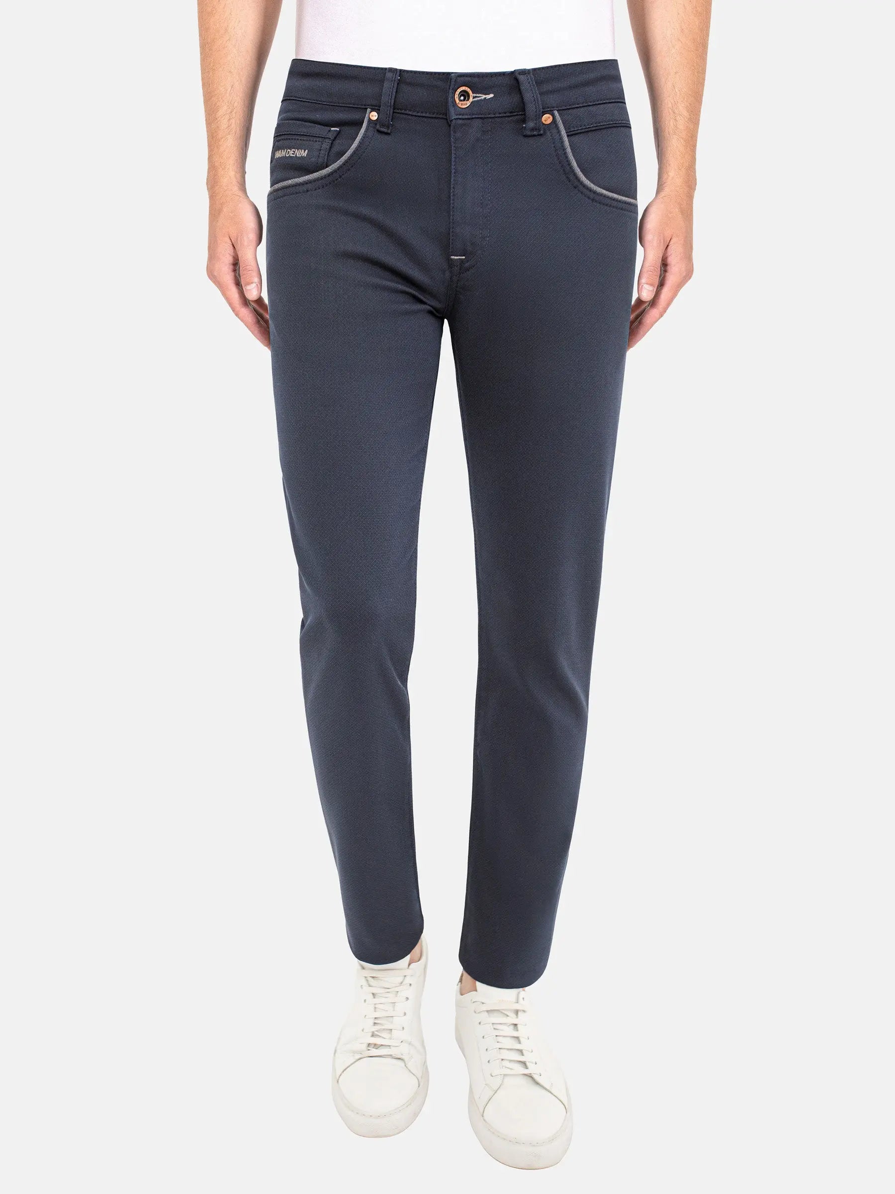 Man wearing dark blue slim-fit jeans with white sneakers. – Wam Denim.