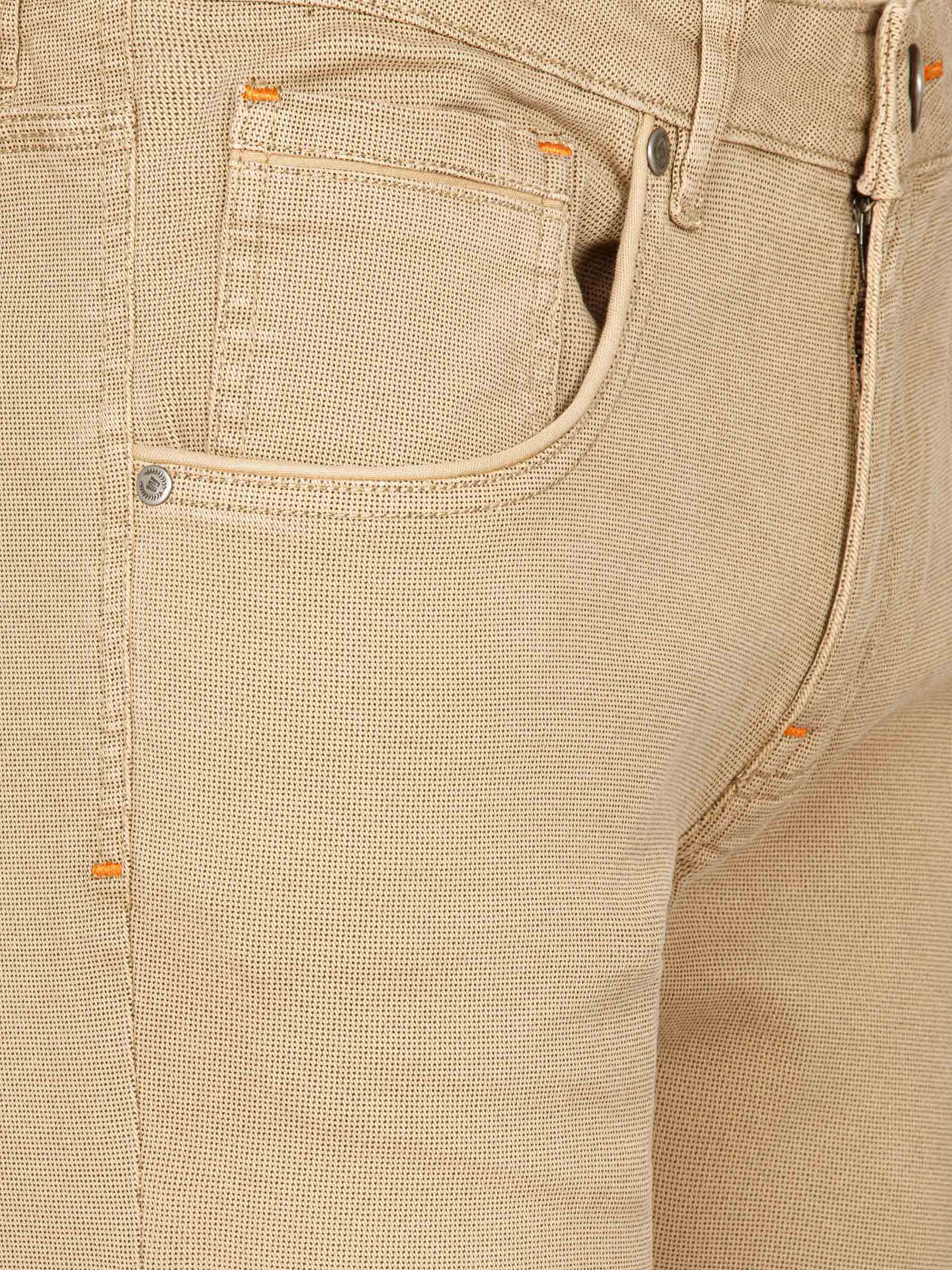 Close-up of beige denim pants with orange stitching and pocket. – Wam Denim.