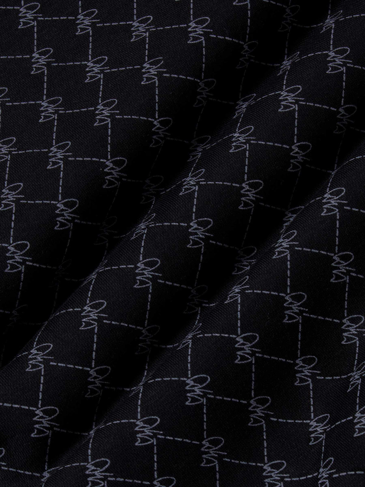 Close-up of black fabric with stitched geometric logo pattern and soft texture – Wam Denim.