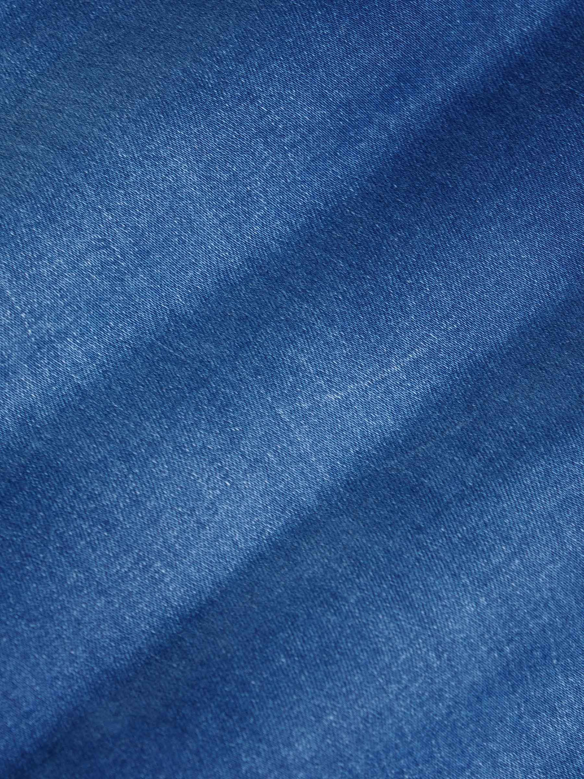 Close-up texture of light blue denim fabric showing fine weave and smooth finish – Wam Denim.