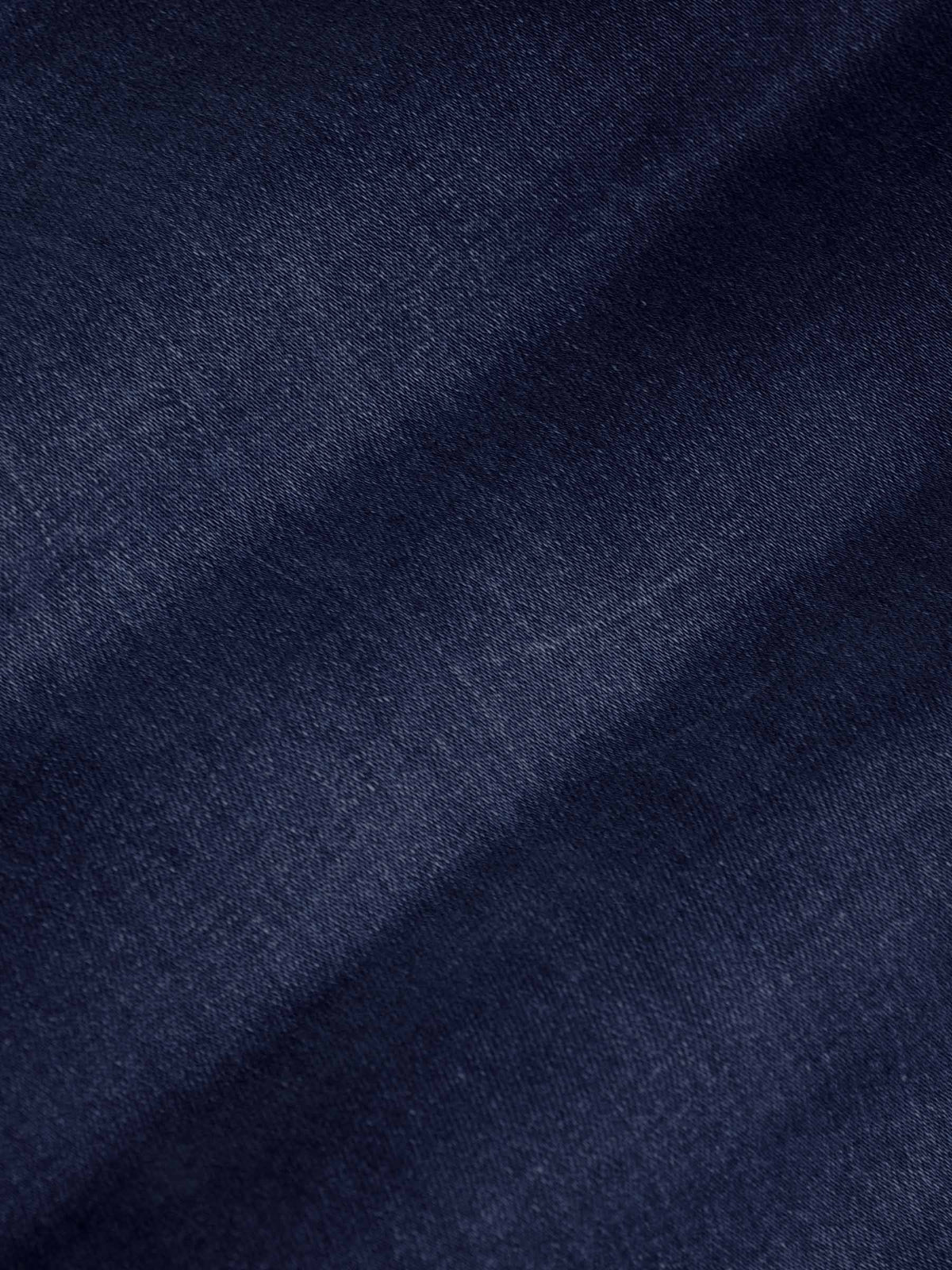Close-up of dark navy denim fabric texture showing smooth weave and slight fade – Wam Denim.