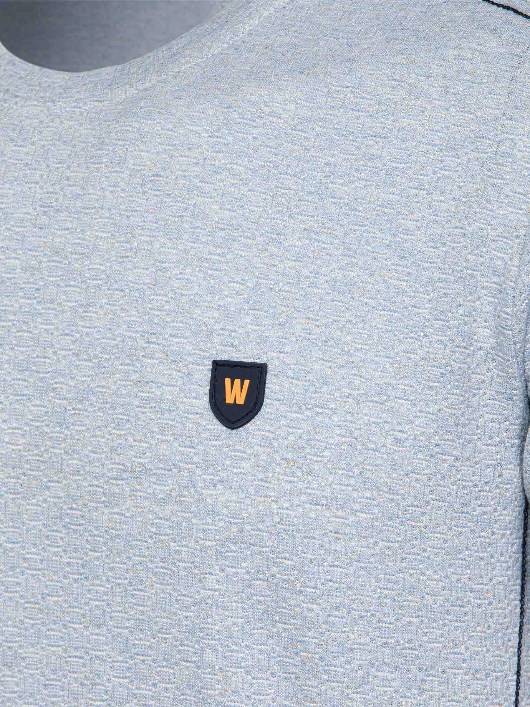 Close-up of the W-shield logo on the blue t-shirt – Wam Denim.
