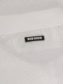 Close-up of the Wam Denim logo on the white polo shirt collar – Wam Denim.