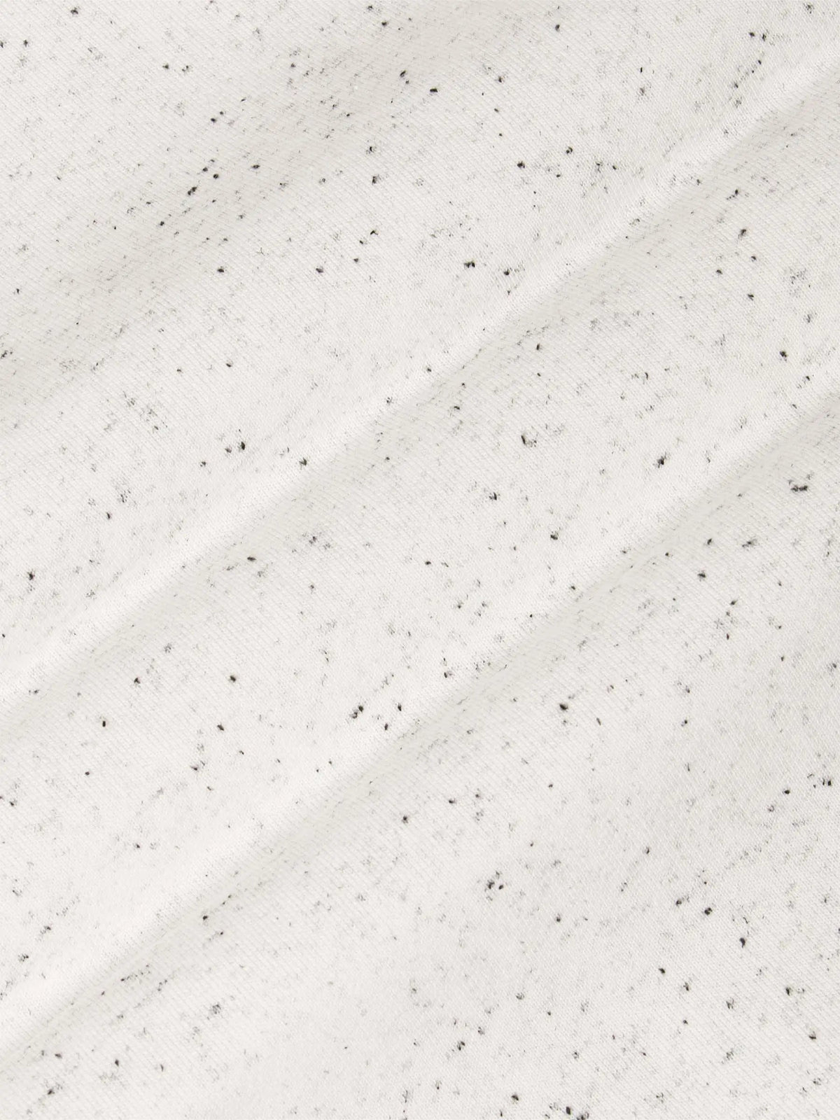 Close-up of a textured white surface with small black specks