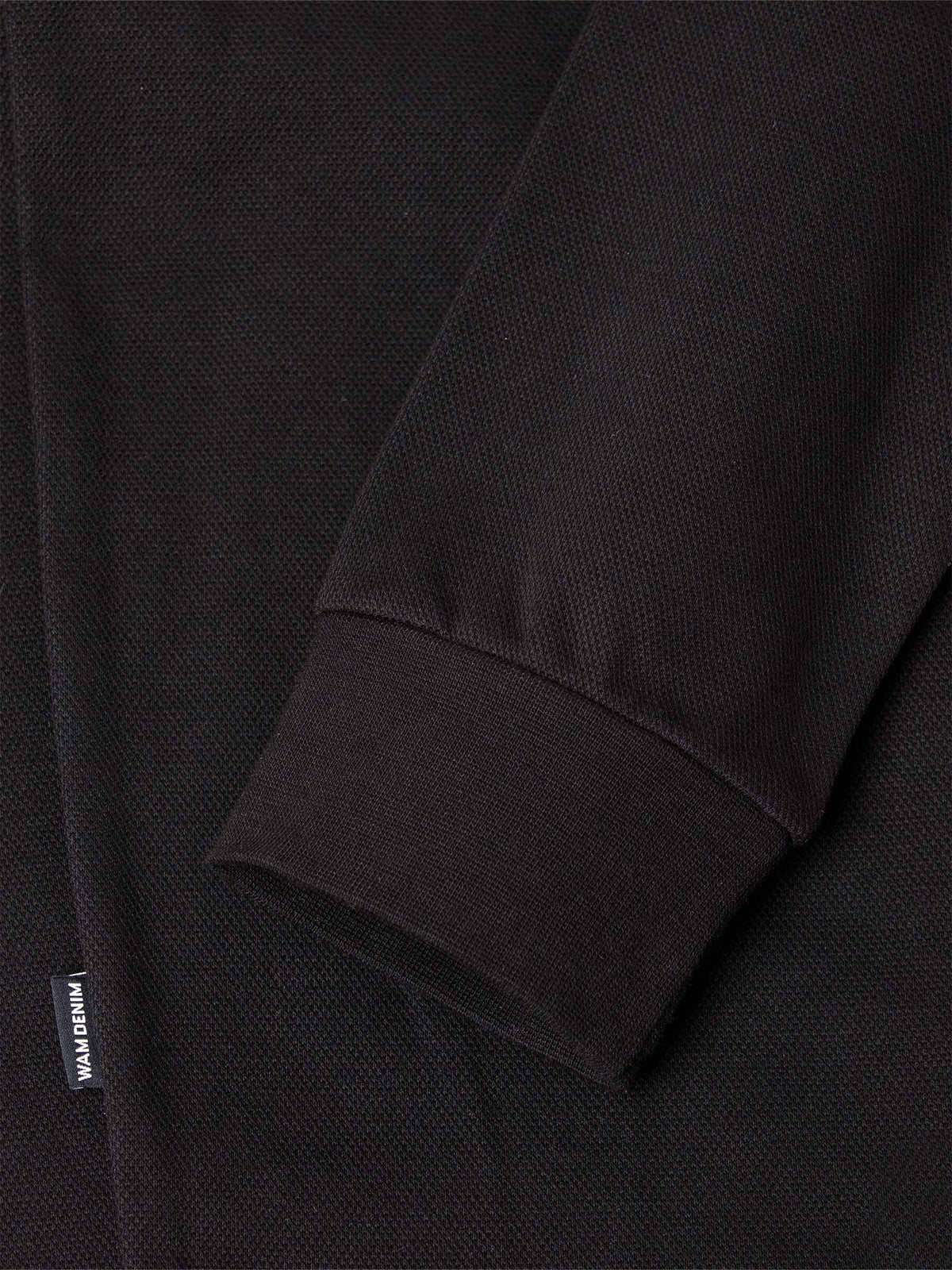 Close-up of black sweater sleeve with ribbed cuff and woven texture detail – Wam Denim.