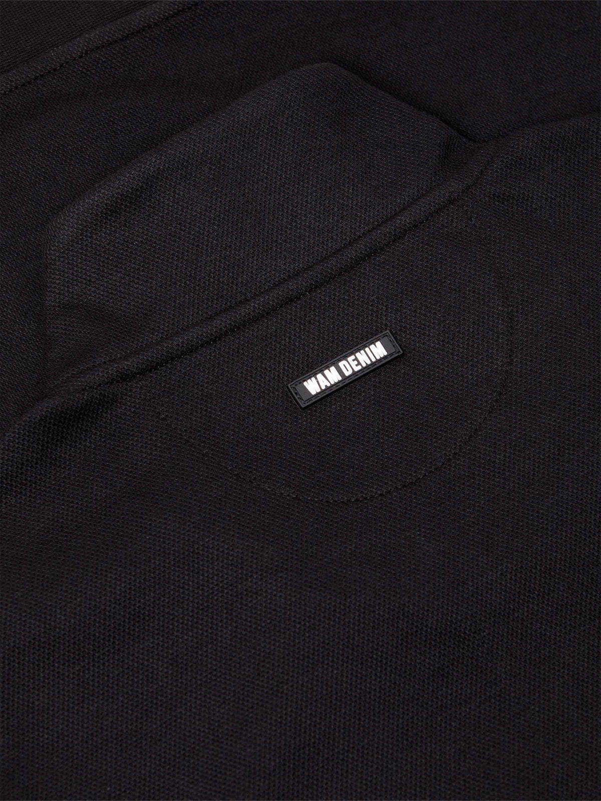 Close-up of black textured sweater fabric with Wam Denim logo tag on the back – Wam Denim.