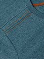 Close-up of shoulder stitching detail with contrast orange seams on petrol knit fabric – Wam Denim.