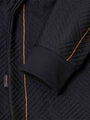 Close-up of sleeve and orange stitch detailing on black textured fabric – Wam Denim.