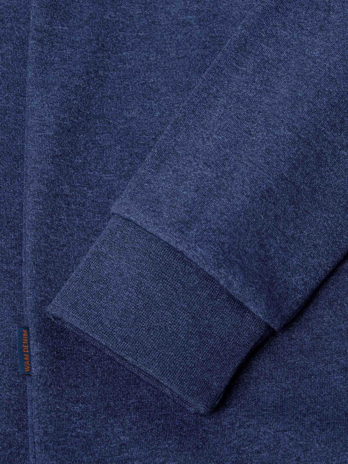 Close-up of ribbed cuff and hem detailing on light indigo sweater fabric – Wam Denim.