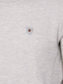 Close-up of light grey textured sweatshirt with brown and grey chest logo patch – Wam Denim.