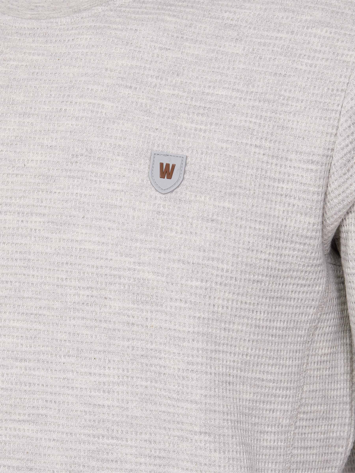 Close-up of light grey textured sweatshirt with brown and grey chest logo patch – Wam Denim.