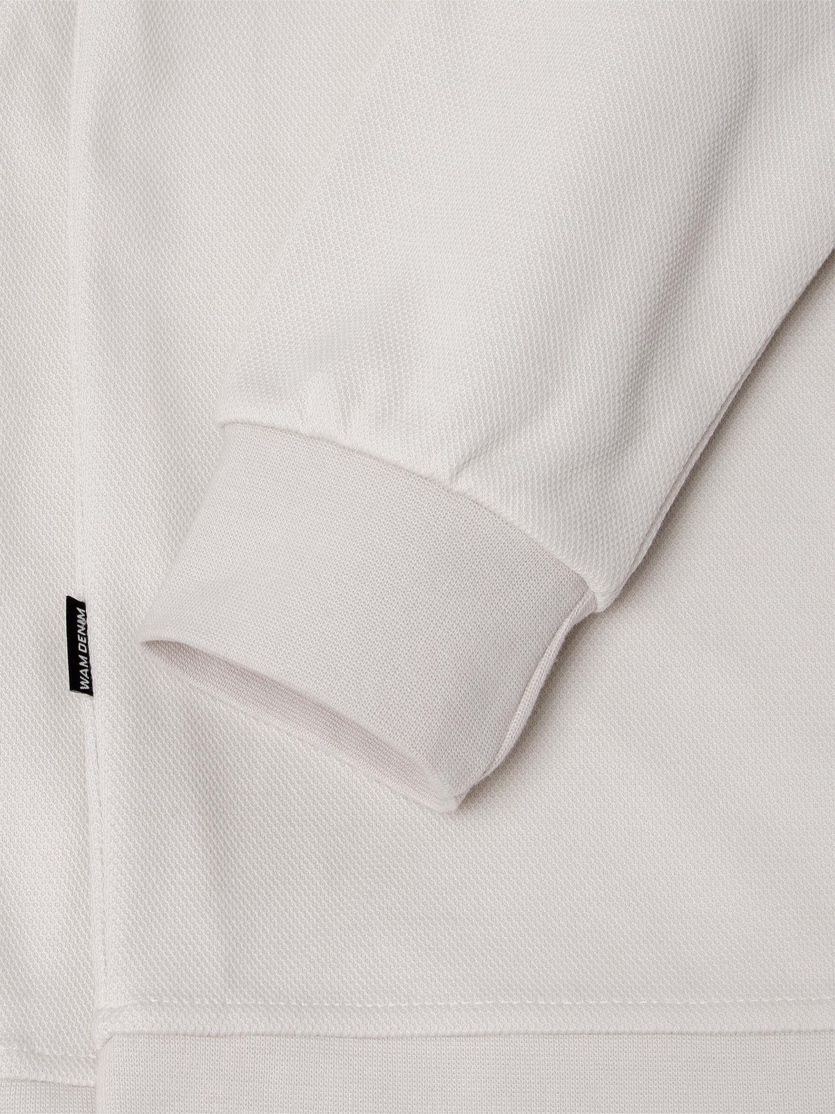 Side view of light beige Milburn Sweater with logo. – Wam Denim.