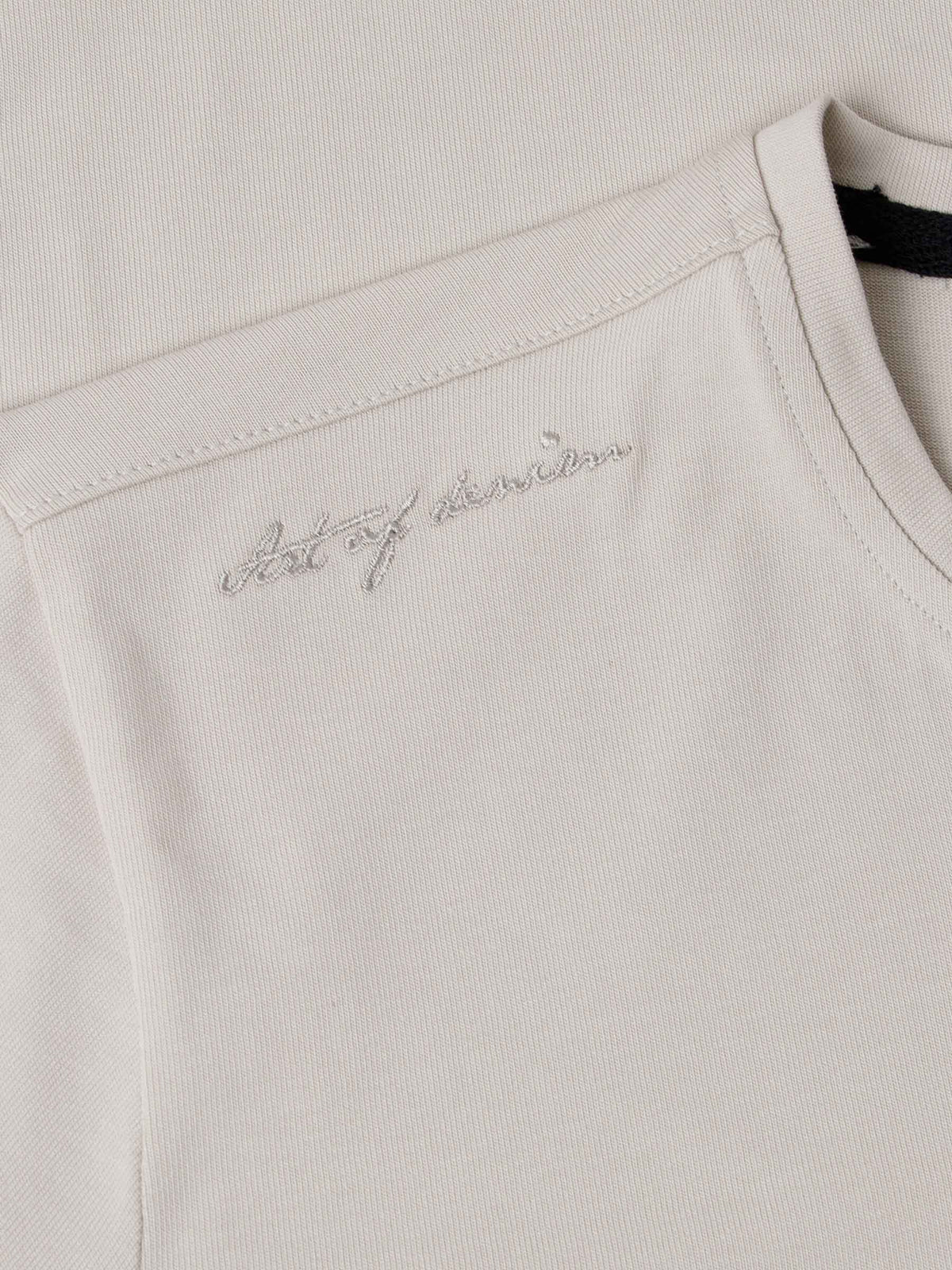 Close-up of The Fervor Light Beige Sweater shoulder embroidery reading “Art of Denim” – Wam Denim.
