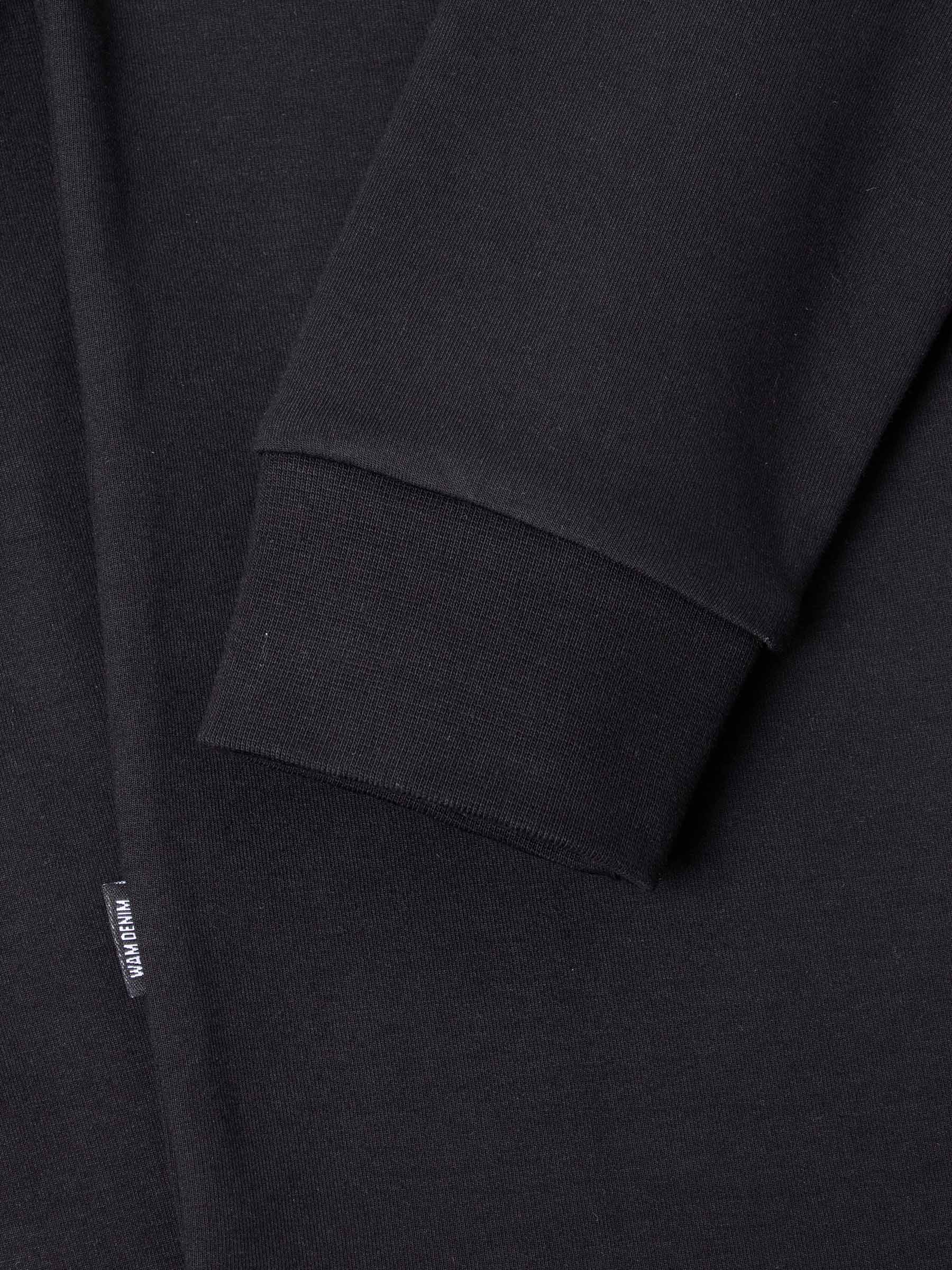 Close-up of The Zeal Black Sweater sleeve cuff showing ribbed finish and woven label – Wam Denim.