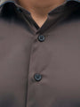 Detail view of light brown men’s shirt with contrast buttons and modern collar.