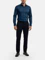 Model wearing petrol blue men’s dress shirt styled with black trousers and formal shoes.
