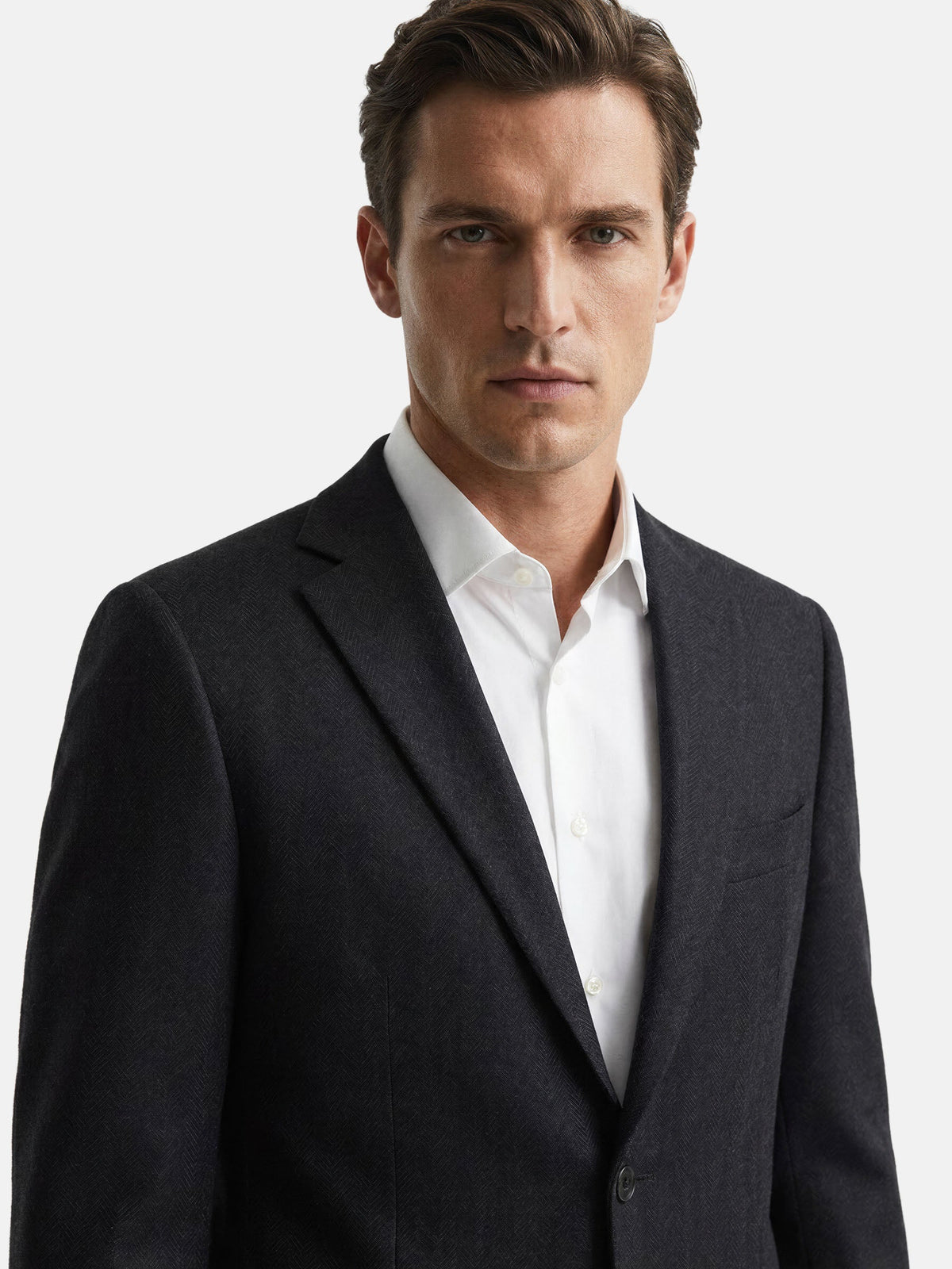 Close-up of male model wearing slim fit black blazer and white shirt.