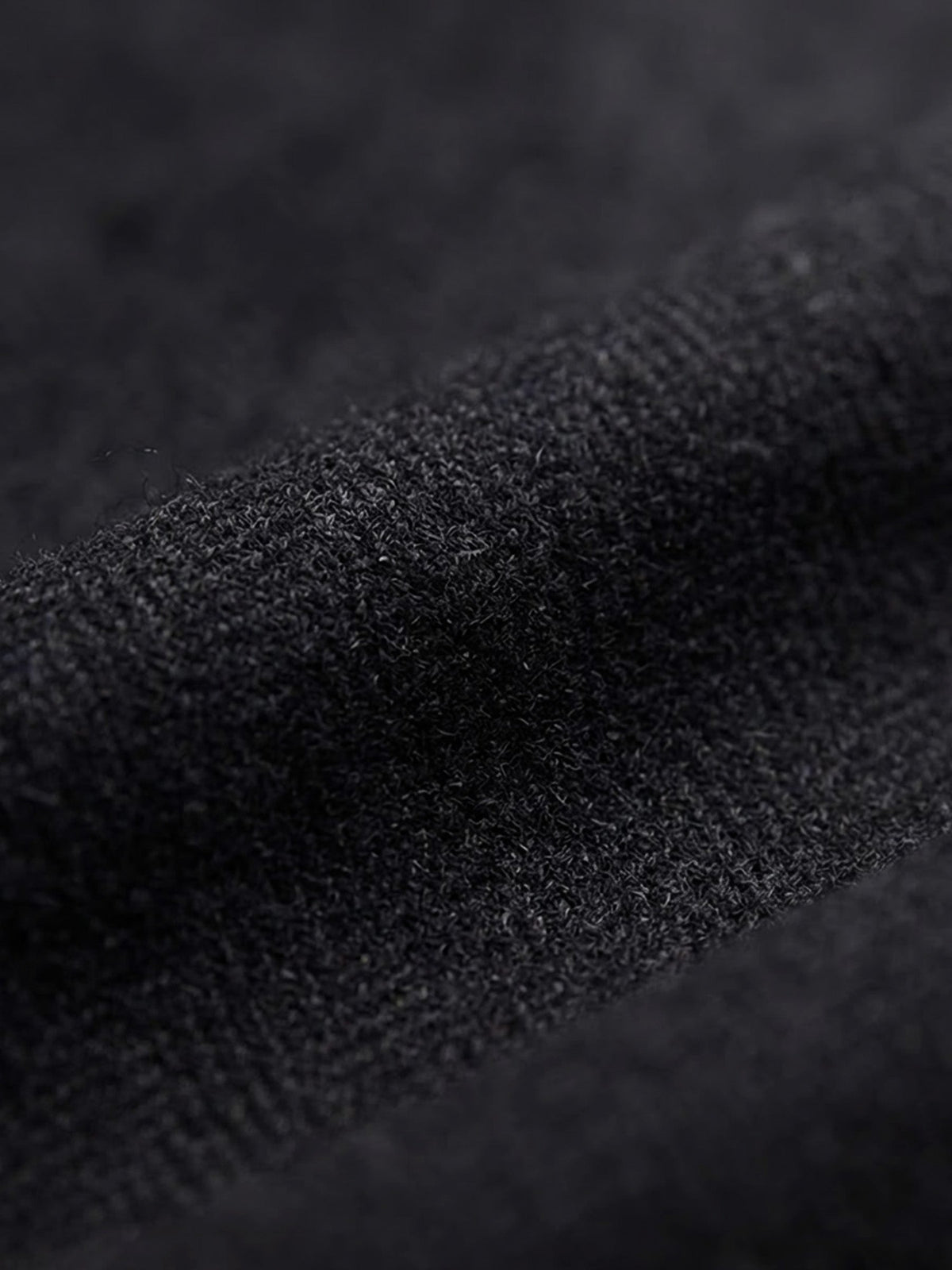 Close-up of black blazer fabric texture with fine woven detail.