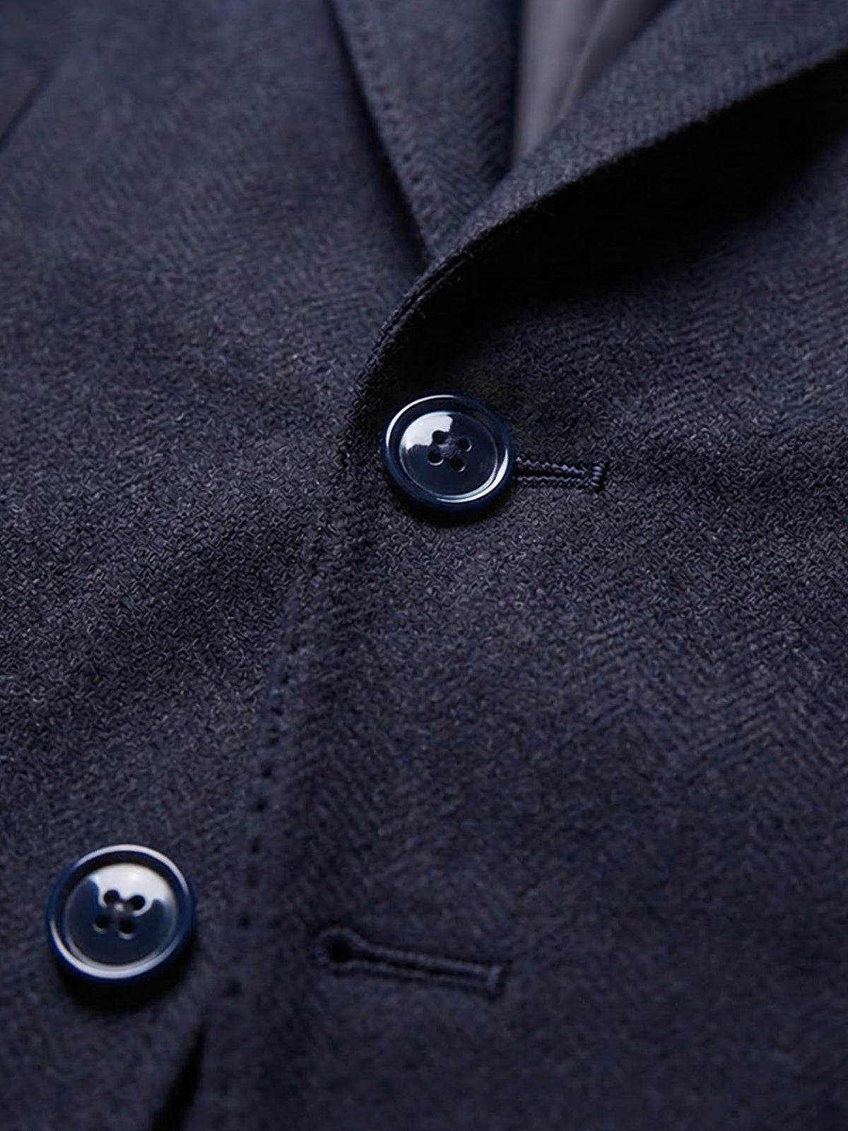 Close-up of navy blazer button and textured fabric detail.