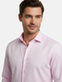 Model wearing pink dress shirt with classic collar, close-up view.