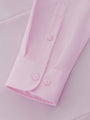 Close-up of pink dress shirt cuff and textured fabric detail.