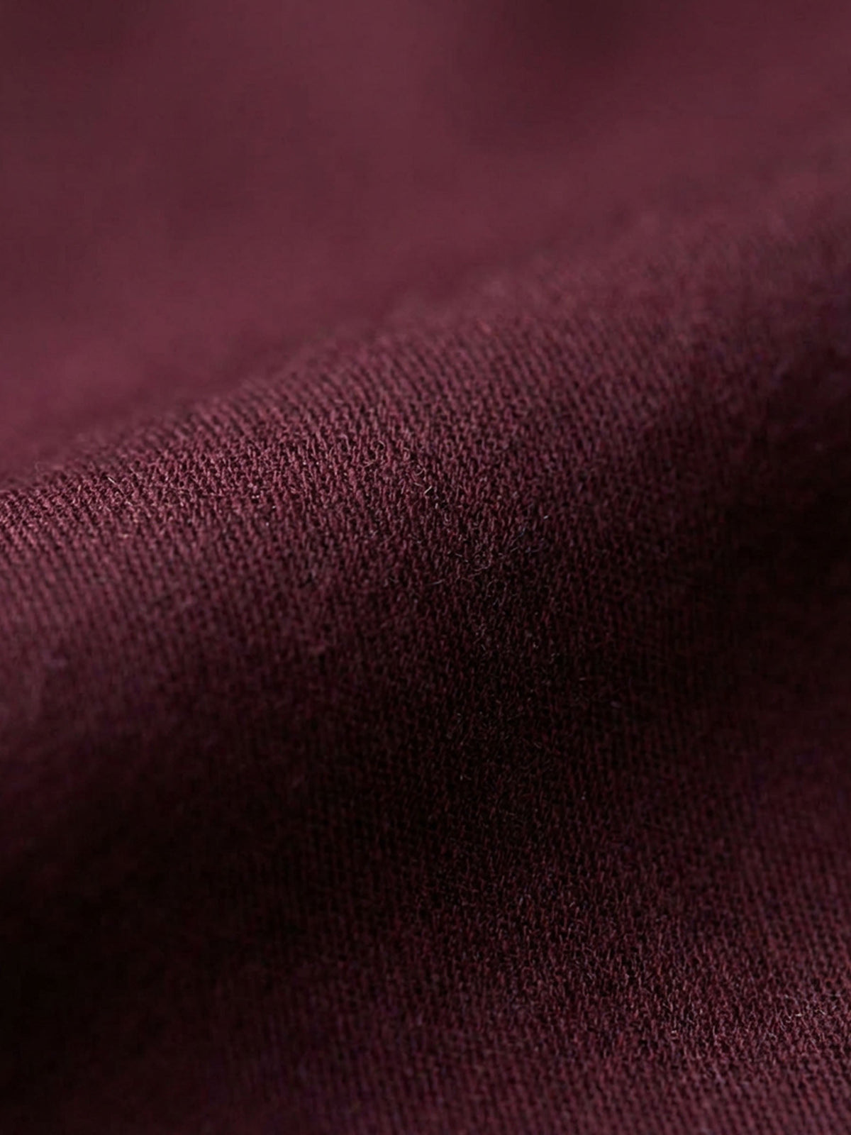 Close-up of dark red men’s shirt fabric showing smooth texture and premium weave