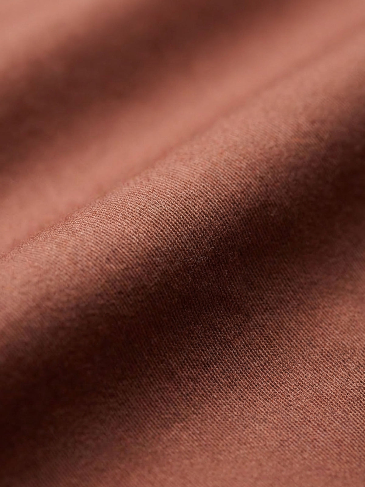 Close-up of light brown men’s shirt fabric showing smooth texture and premium weave