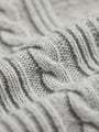 Close-up of light grey knit sweater fabric showing detailed cable-knit texture.