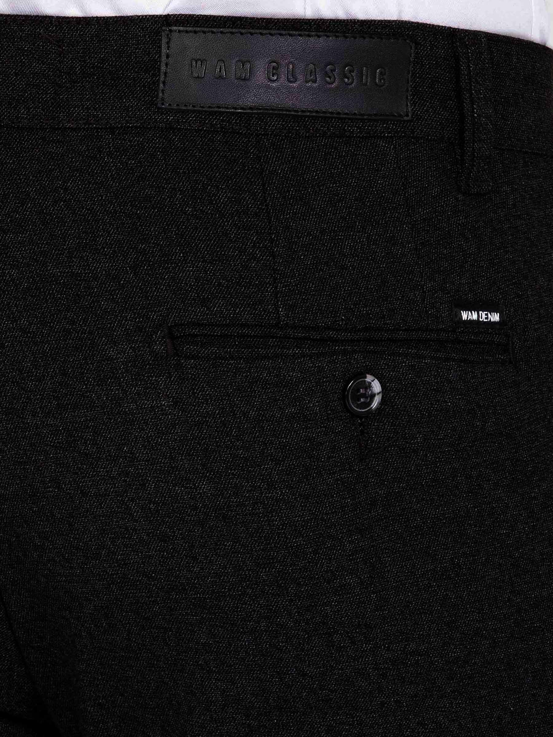 Close-up of dark grey chino trousers showing back pocket, button detail, and Wam Denim label.