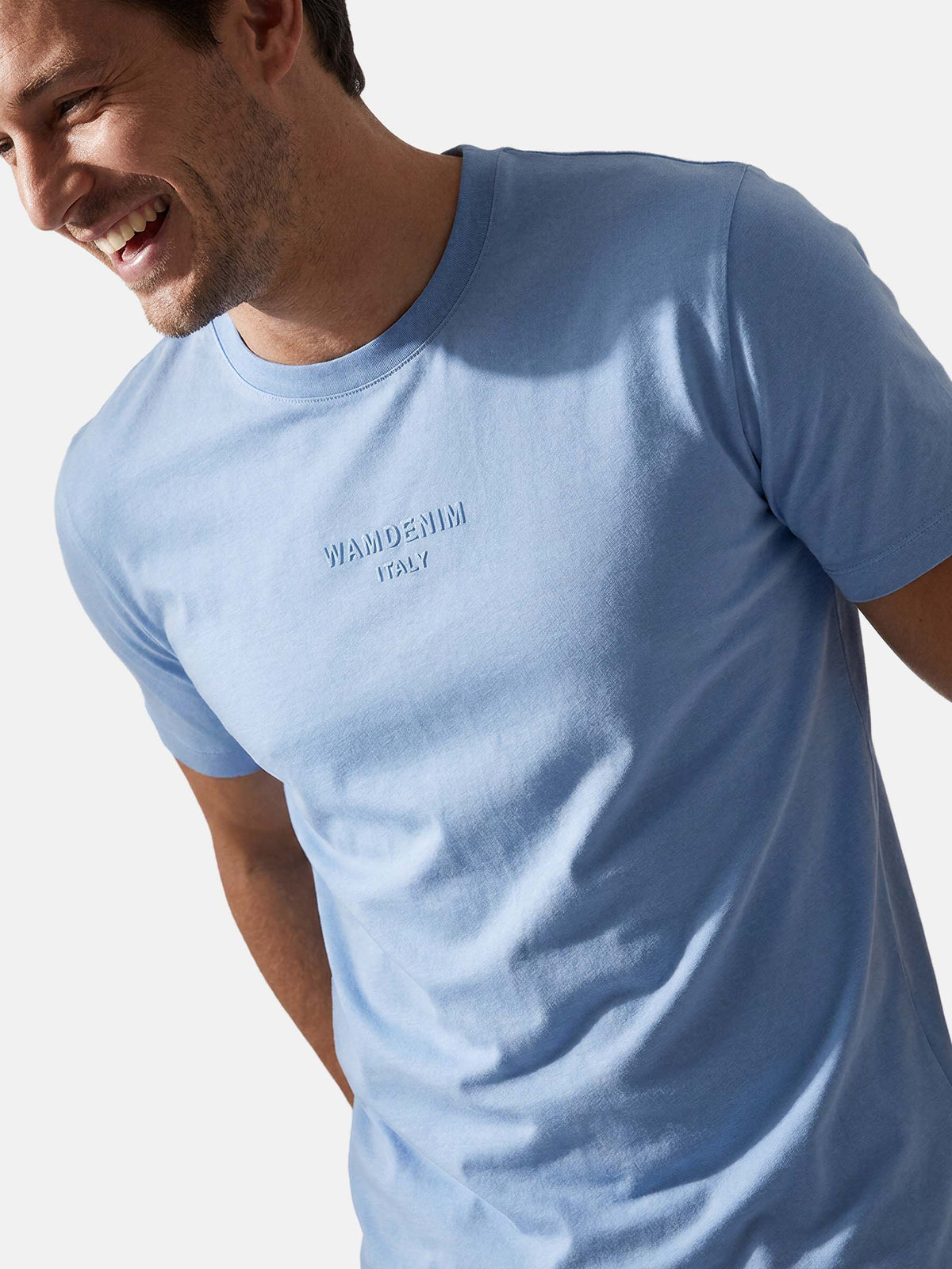 Close-up of men’s light blue crew neck T-shirt with subtle logo detail