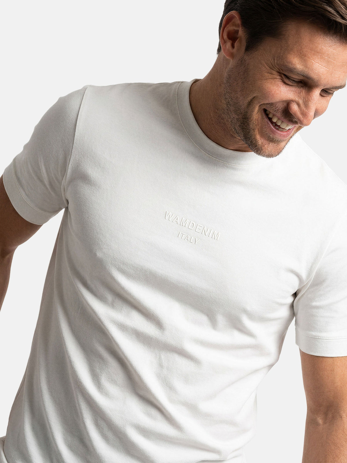 Close-up of white men’s crew neck T-shirt with subtle logo print detail
