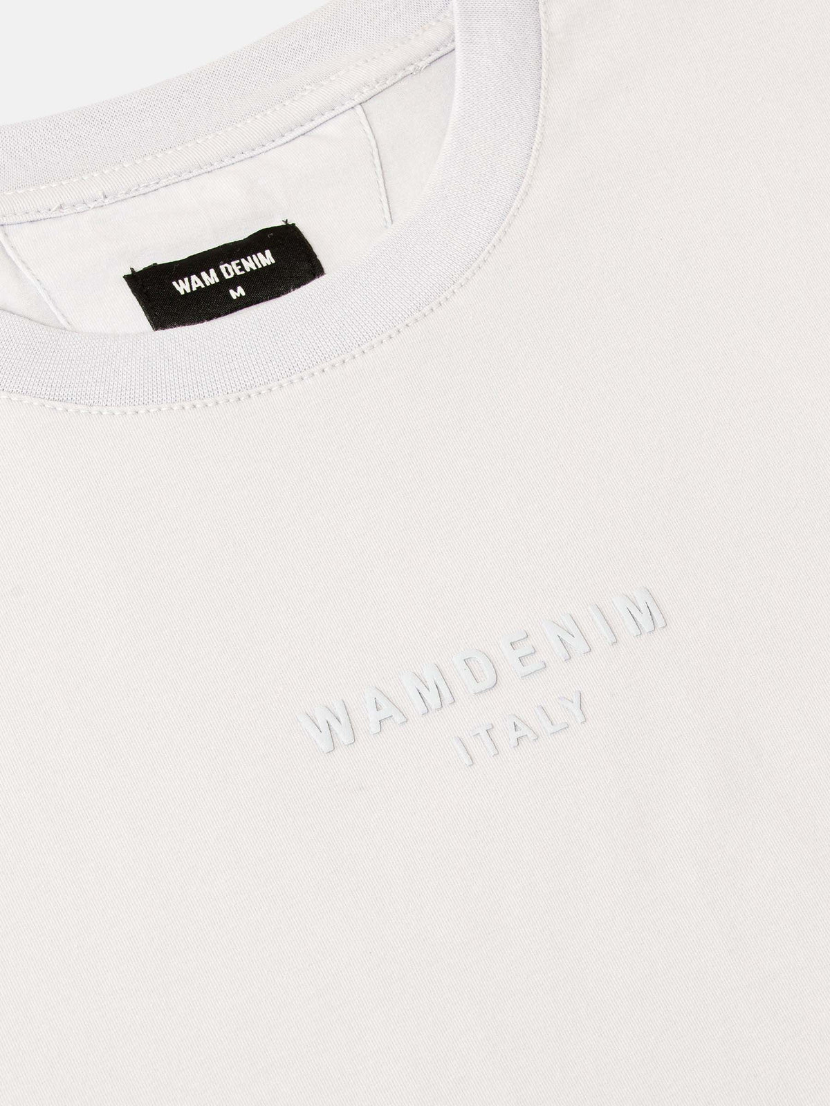 Close-up of white crew neck T-shirt with embossed Wam Denim logo detail