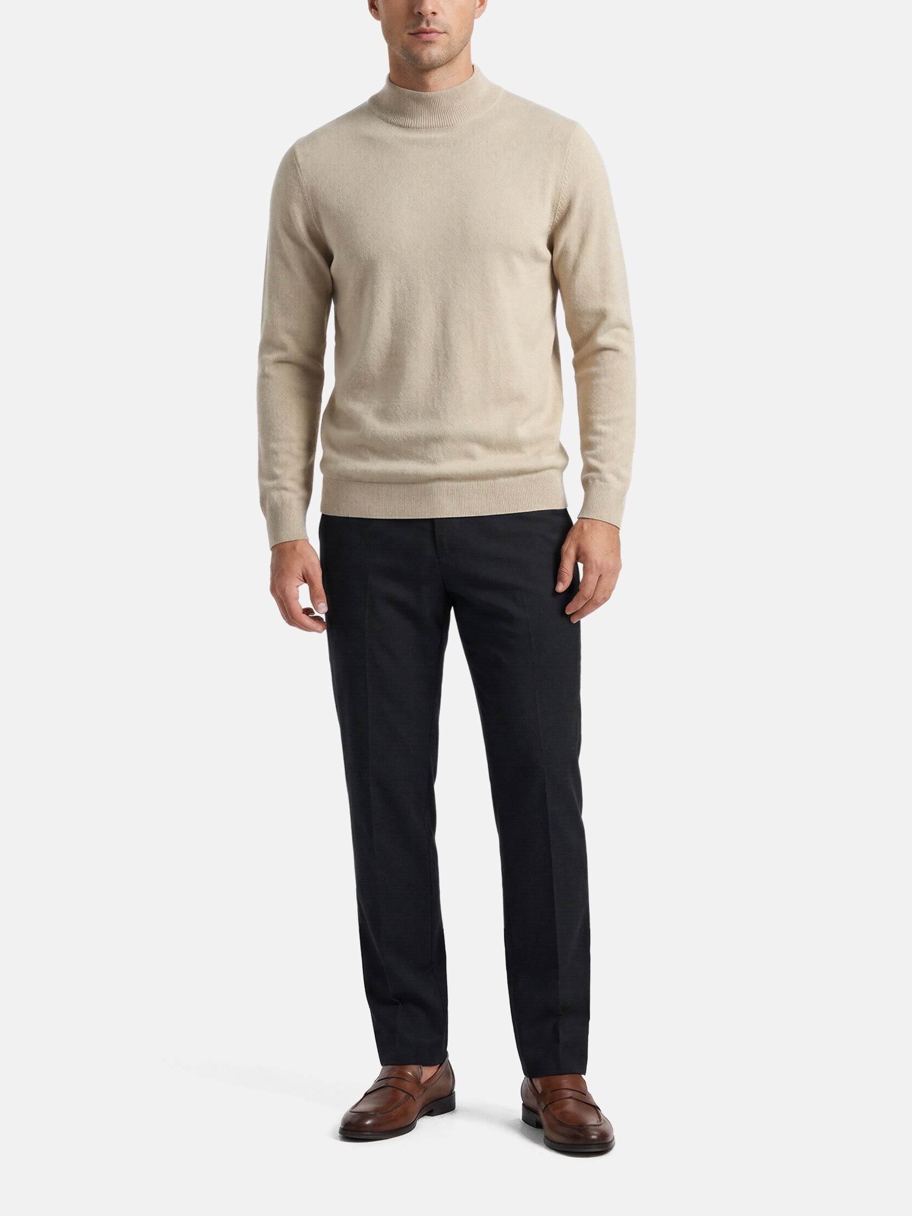 Man wearing a beige mock-neck pullover styled with dark trousers and brown loafers.