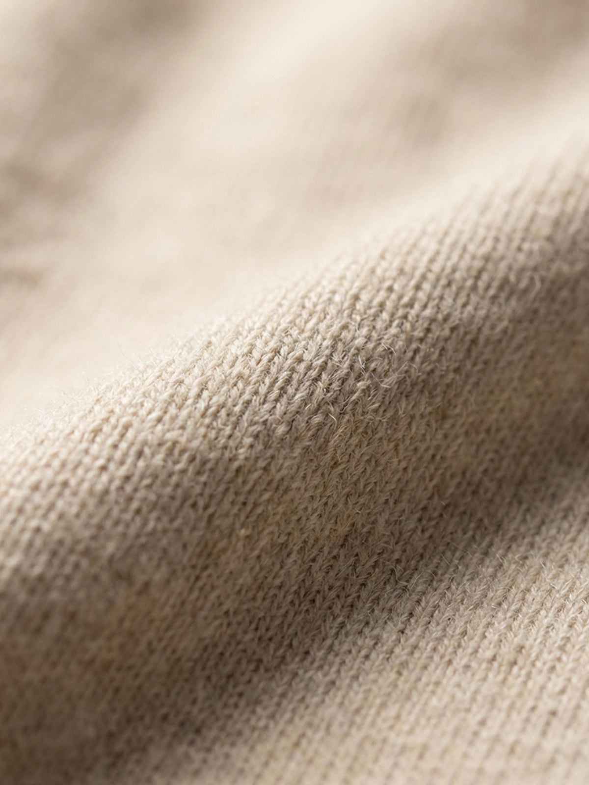Close-up of beige pullover knit fabric showing soft, textured material detail.