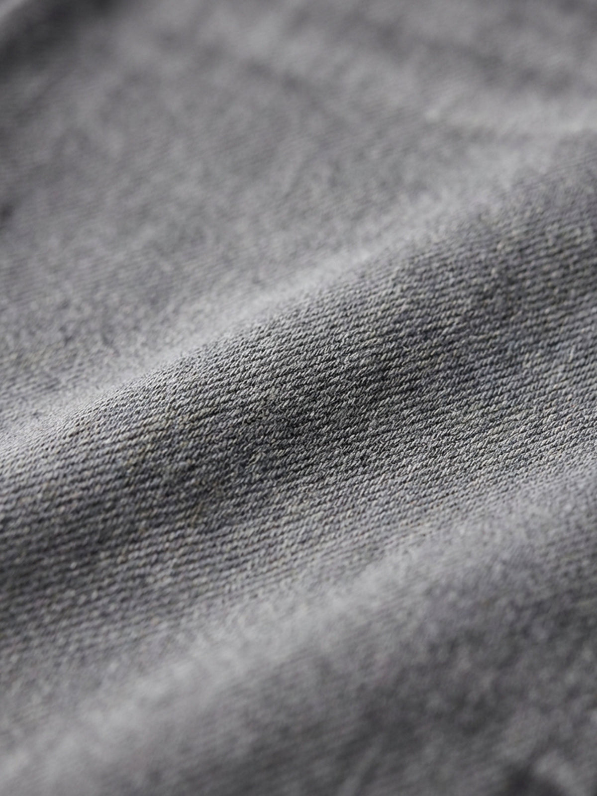 Close-up of grey denim fabric showing soft texture and washed finish.