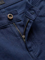 Detail of navy denim jeans with branded button, zipper, and reinforced stitching